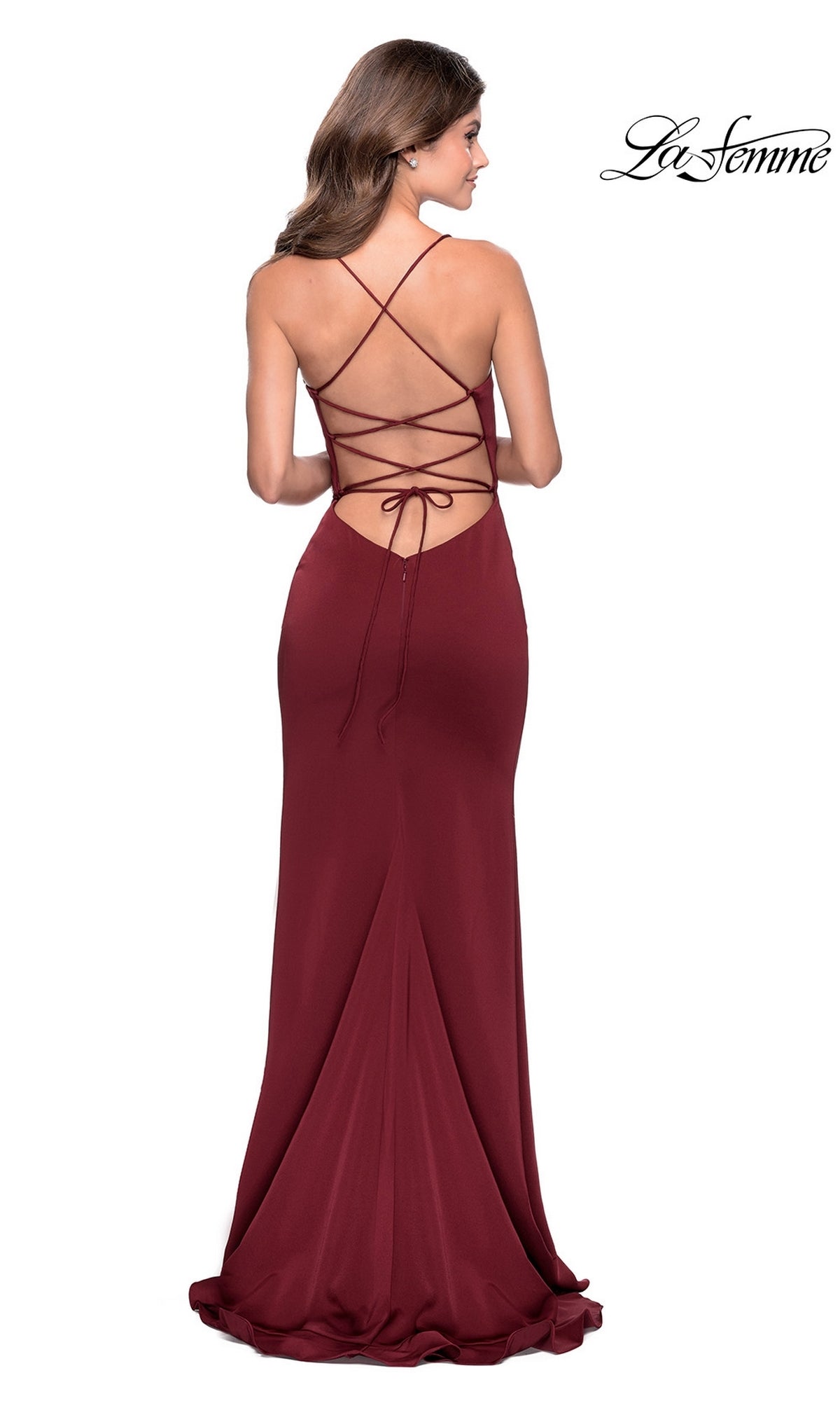 A woman wearing a floor-length, fitted La Femme Side-Ruffle Long Prom Dress 28294 in burgundy with open back and crisscross lace-up straps stands against a white background.